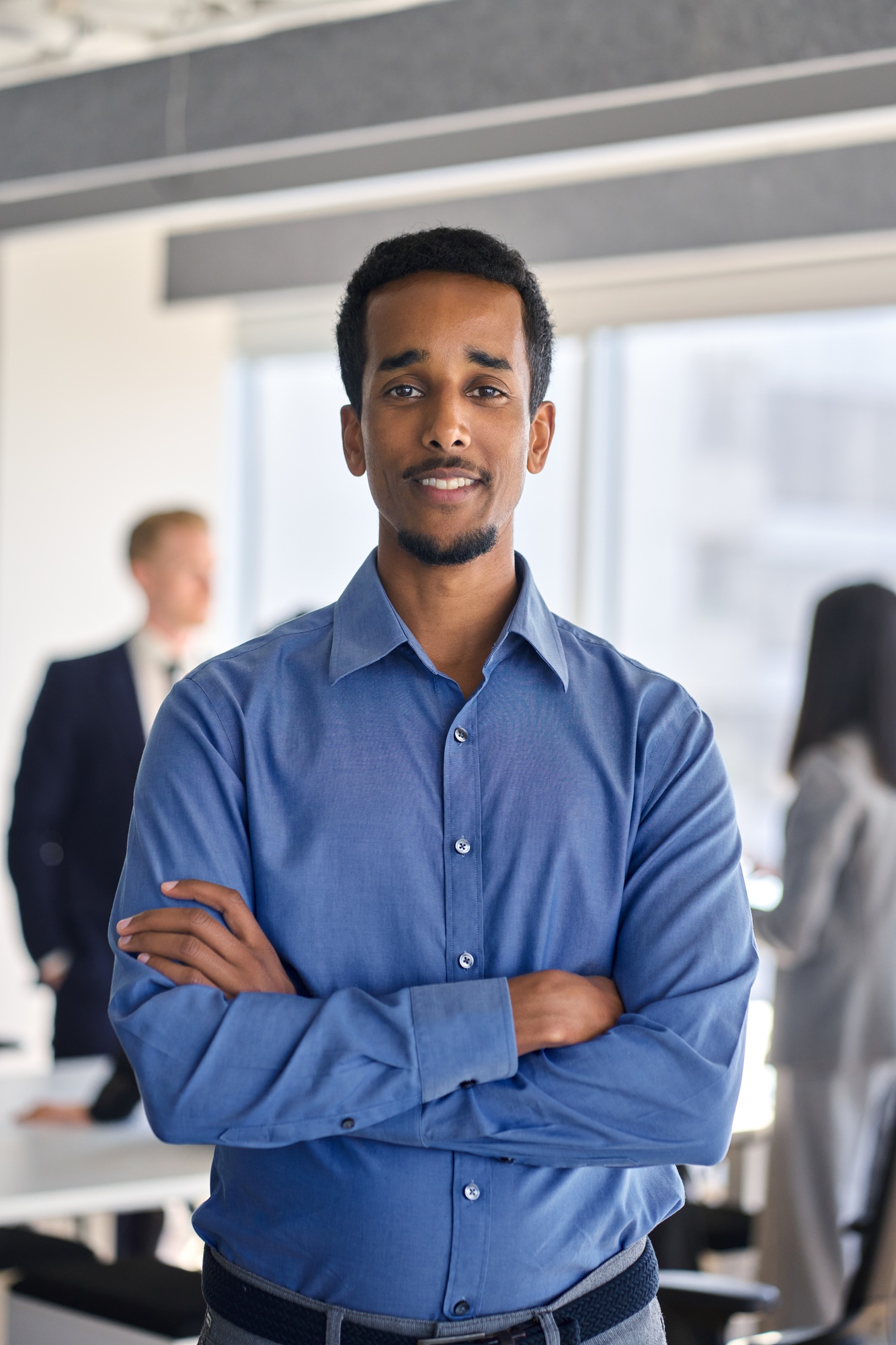 Confident African American business man standing in office, vertical portrait.